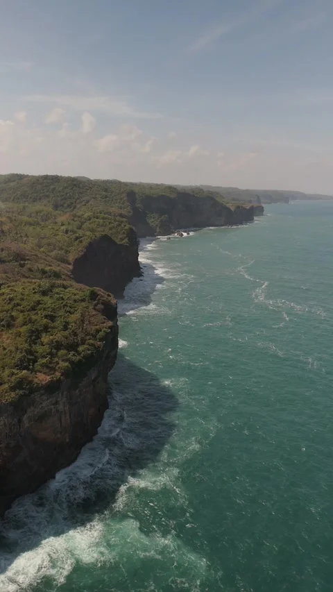 Vertical mode aerial view of massive cliffs jutting down into the sea Stock Footage 293714707
