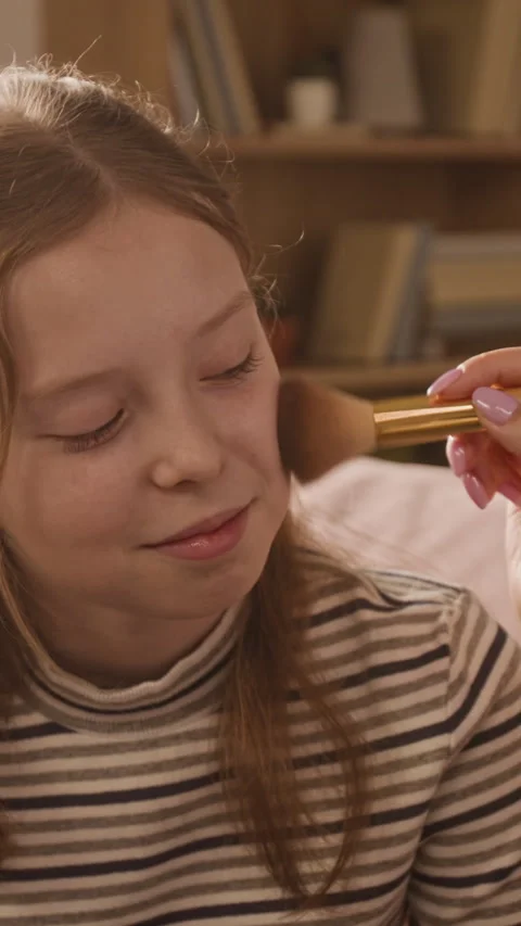 Vertical of Mom Putting Blush on Face of Smiling Girl Child at Home Stock Footage 334341546