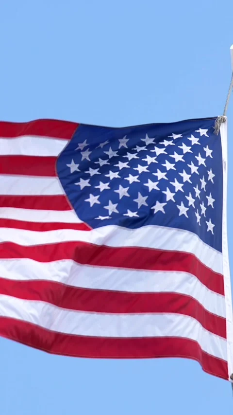 Vertical motion of USA flag blowing in strong wind with vivid blue sky Vidéo 316459509