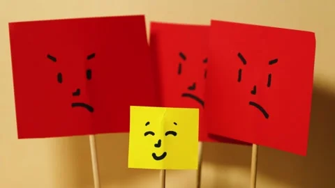 Vertical motion of yellow paper with happy square face surrounded by red angry Video stock 291647500