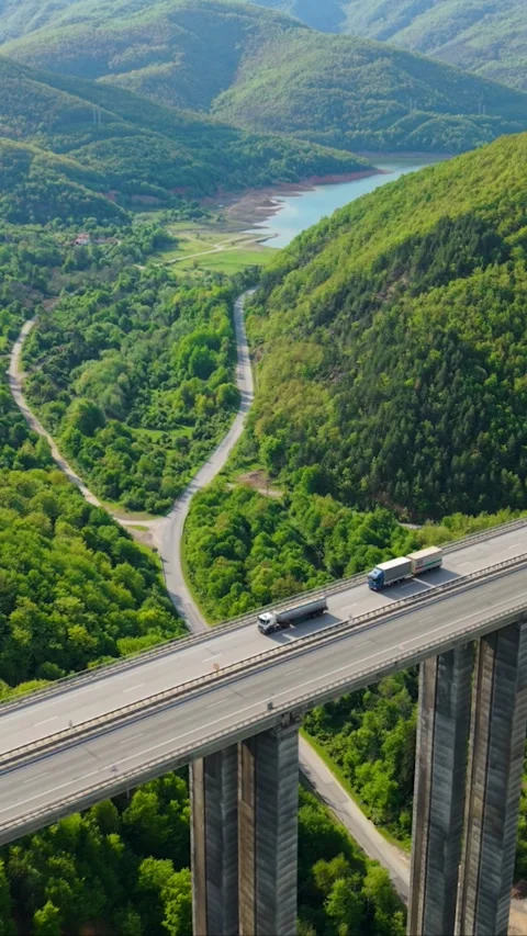 Vertical Mountain Viaduct Highway with Moving Traffic Surrounded by Green Hills Stock Footage 310357557