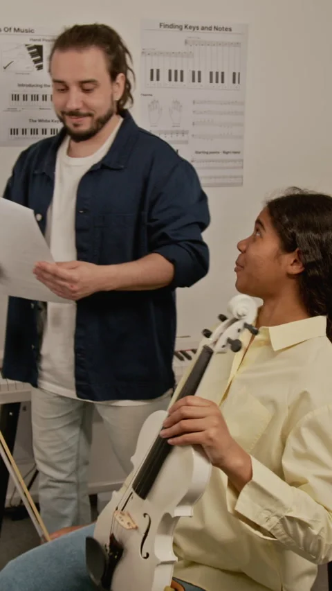 Vertical of Music Teacher Explaining Notes to Female Student with Violin Stock Footage 339185699