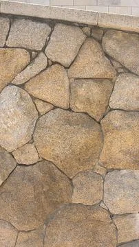Vertical natural stone wall texture with irregular shapes and warm earthy ton Stock Photos
