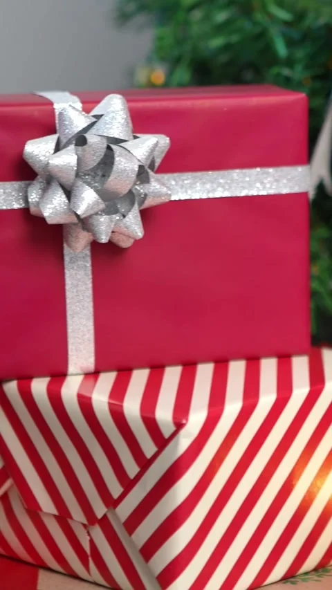 Vertical Neatly wrapped gift boxes beneath the Christmas tree in a home Stock Footage 313075786