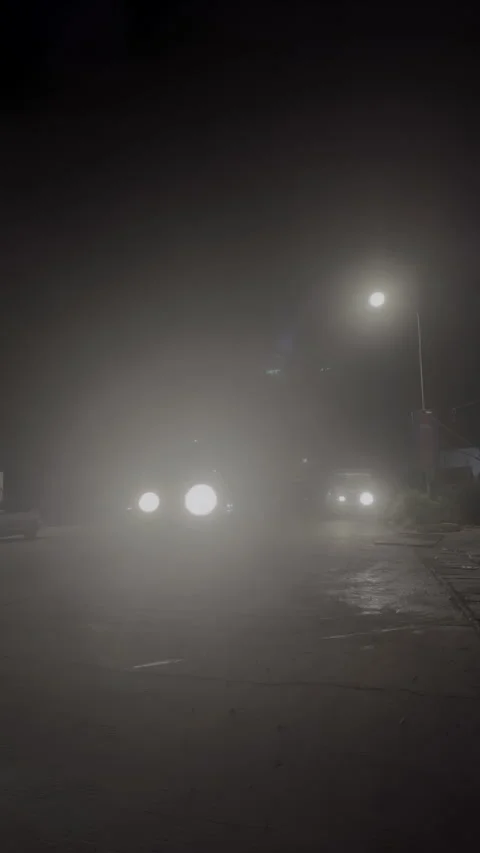 Vertical night shot: garbage truck turning under lamp, traffic behind Stock Footage 338420979
