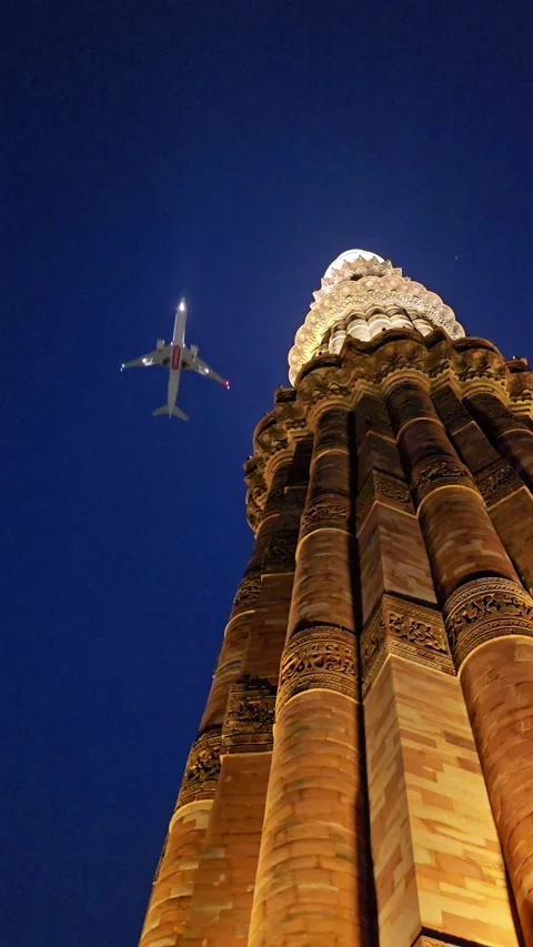 Vertical Night View of Qutub Minar with Airplane Flying Over Delhi India Stock Footage 337880434