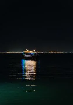 .Vertical Night View of Traditional Qatari Dhow Boat Illuminated  Photos