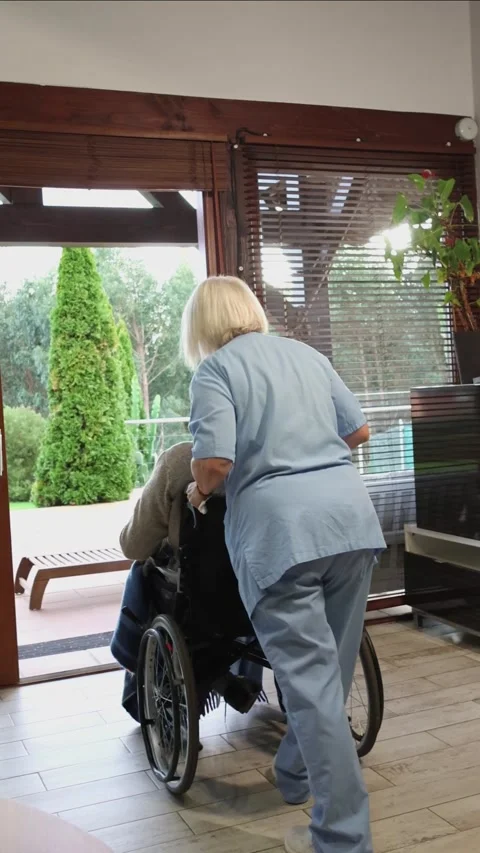 Vertical Nurse pushing elderly man in wheelchair towards garden Stock Footage 300172168