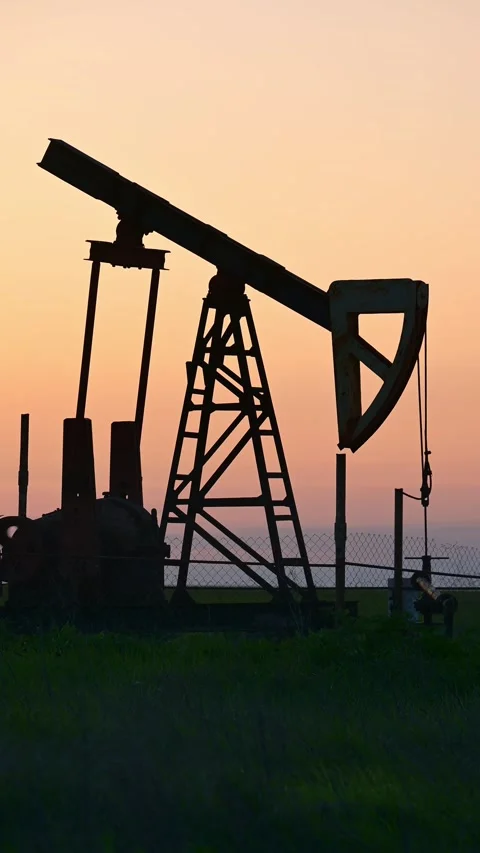 Vertical Oil Pump Jack Silhouette at Sunset over Green Field Stock Footage 333037550