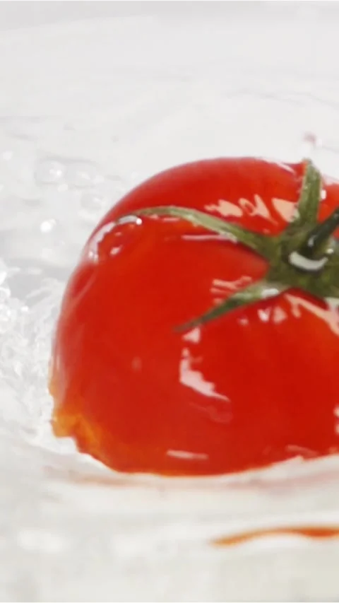 Vertical of One red ripe tomato with green leaves falls under water Stock Footage 305518095
