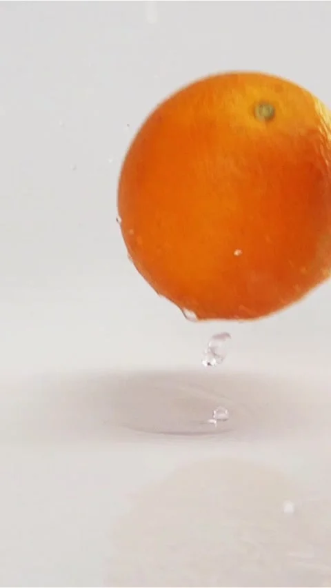 Vertical of Oranges falling and bouncing on grey wet surface Stock Footage 305478609