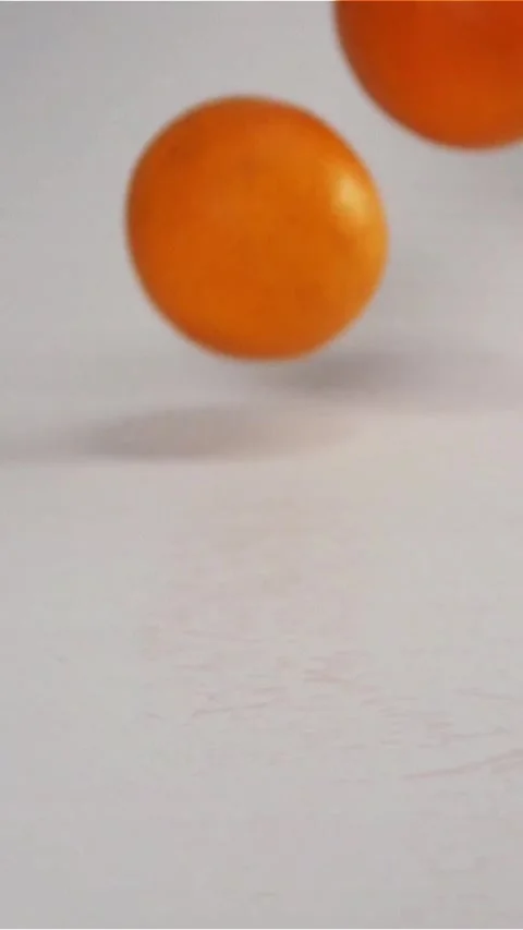 Vertical of Oranges falling and bouncing on white wet surface Stock Footage 305517377