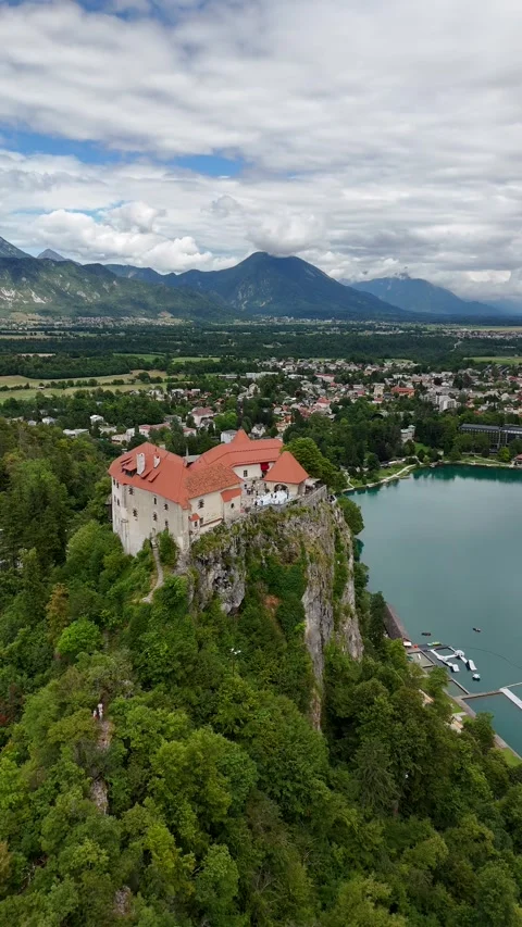 Vertical orbit drone view of a majestic mountain castle and crystal lake Stock Footage 322045484