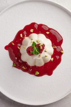 Vertical orientation panna cotta with raspberry syrup, pistachios, berries and Stock Photos