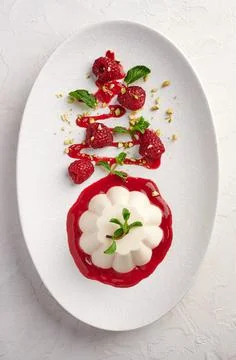 Vertical orientation panna cotta with raspberry syrup, pistachios, berries and Stock Photos