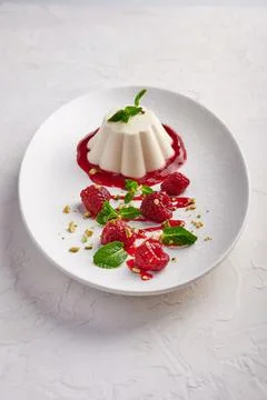 Vertical orientation panna cotta with raspberry syrup, pistachios, berries and Stock Photos