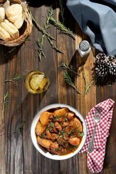 Vertical oriented overhead view of a wooden table with a plate of meat stew w Stock Photos