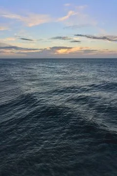 A vertical oriented photograph of sea waves under an early morning sunrise sky Stock Photos