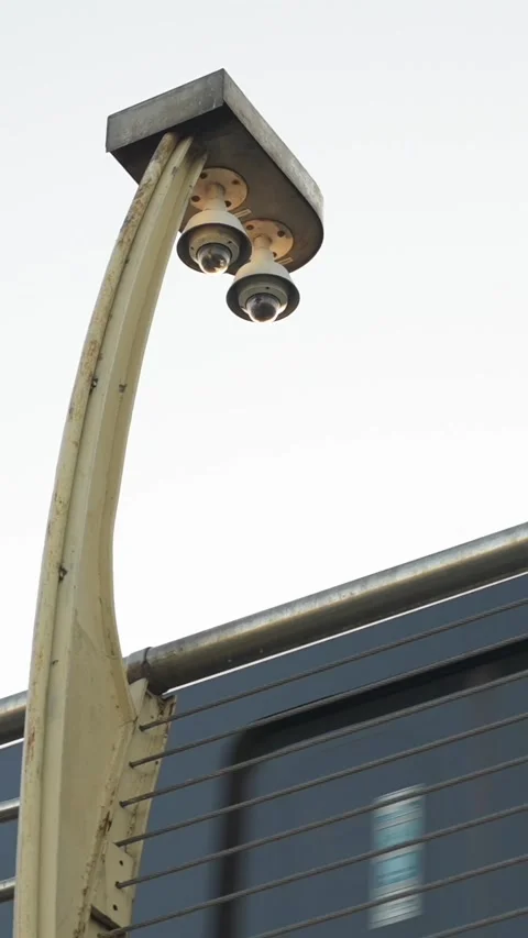Vertical outdoor security camera on a pole above a passing subway train on the Stock Footage 303739418