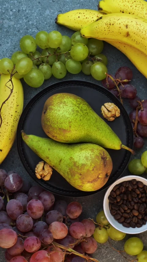 Vertical overhead loop of pears with grapes bananas coffee beans and walnuts Stock Footage 320029195