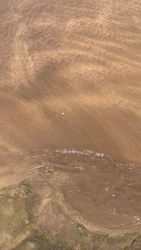 Vertical Overhead Shot of Murky Water Flowing Over Sand Bed Stock Footage 340775135