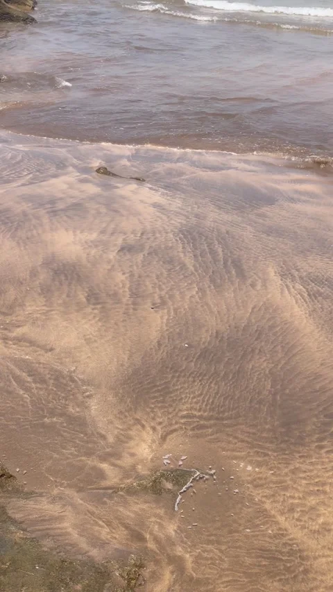 Vertical Overhead Shot of Soft Foam Receding Over Rippled Sand Stock Footage 340775129