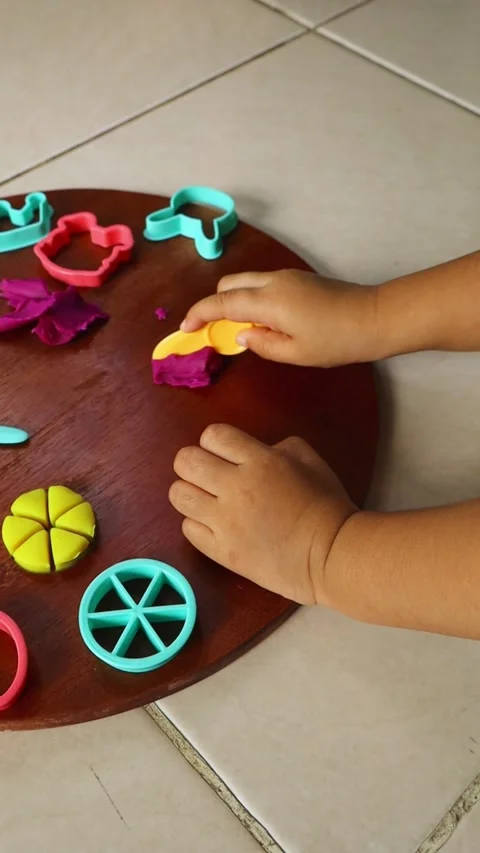 Vertical overhead view of a child using plastic cutters and tools on playdough. Stock Footage 345766696