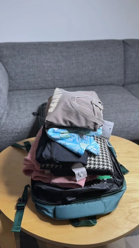 Vertical Packing Scene — Man Stacking Folded Clothes into Backpack for Travel Stock Footage 320078789