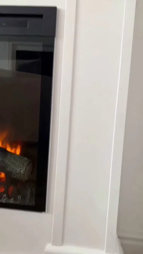 Vertical pan up shot of handcrafted white fireplace mantel and electric flame Stock Footage 341829192