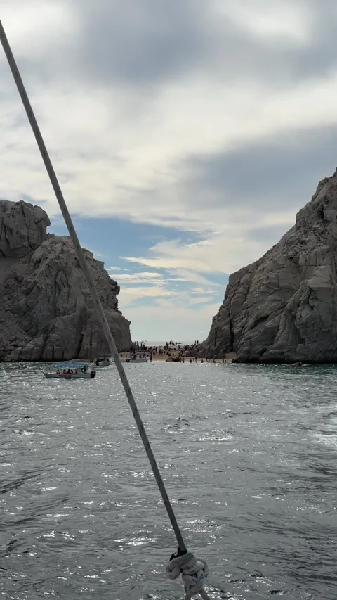 Vertical Pan from Small Beach with People to Massive Rock Formations in the Sea Stock Footage 313971970