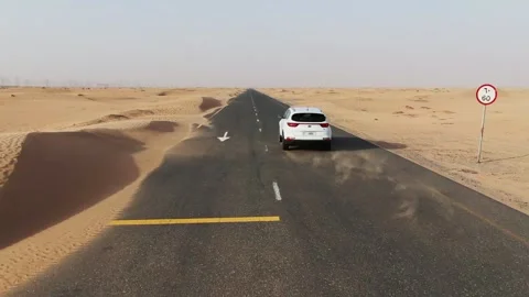 Vertical panning from a quadcopter. White car is driving on road in the desert Stock Footage 158008166