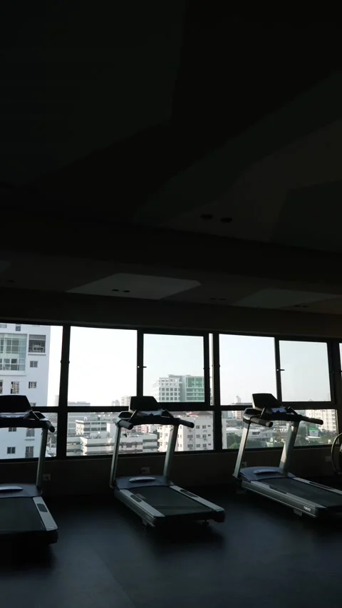 Vertical panning shot of empty treadmills in gym in front of panoramic windows Stock Footage 201080997