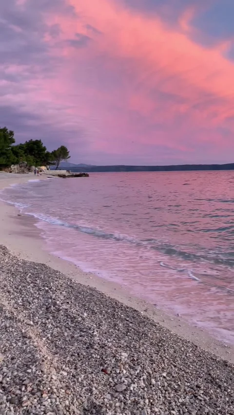 Vertical - Panning Shot Of Pink Sunset Over Waves On Pebble Beach In Croatia Stock Footage 345277823