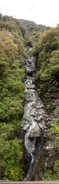 Vertical panoramic view of mountain stream flowing into glacial valley of Fra Stock Photos