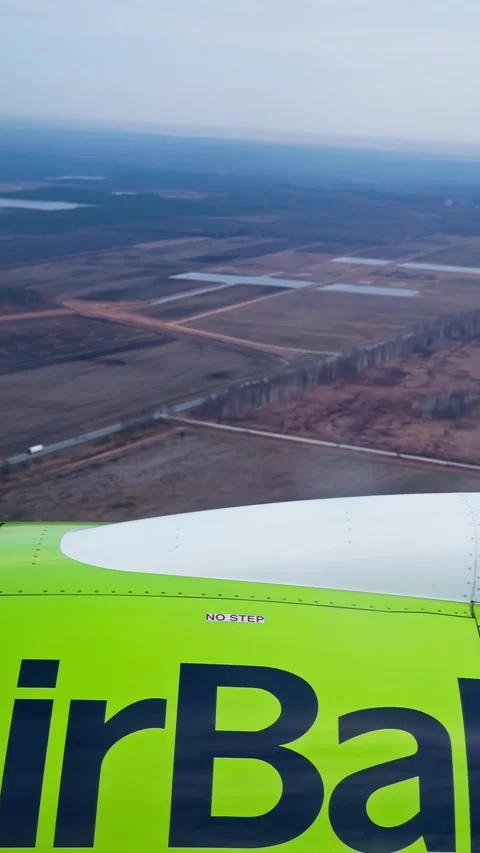 Vertical passenger-seat view of an airBaltic aircraft engine and wing above Stock Footage 334789147