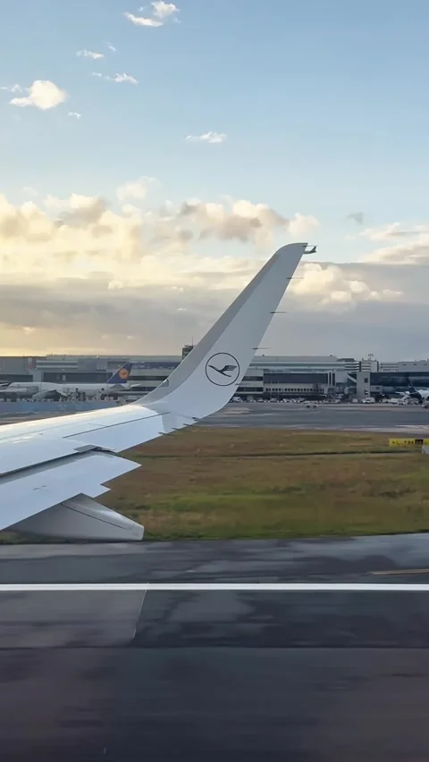 Vertical passenger-window view of a Lufthansa wing taxiing at Frankfurt Airport Stock Footage 345095587