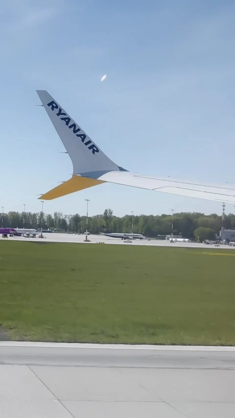 Vertical passenger window view of Ryanair wing at Krakow Airport, with runway Video stock 338003214