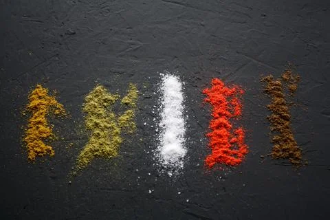 Vertical paths of different spices located on a black surface. Stock Photos