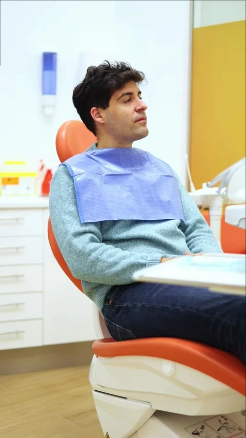 Vertical Patient slowly turning head while sitting on dentist chair, waitin.. Stock Footage 295784540