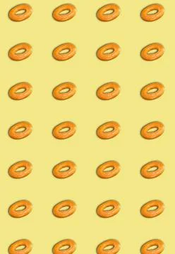 Vertical pattern of bagels on a yellow background. Bakery template. Stock Photos