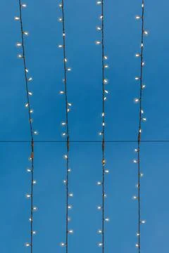 Vertical pattern of glowing Christmas lights against a blue twilight sky Stock Photos