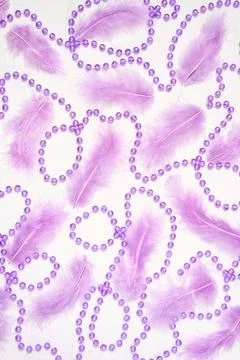 Vertical pattern of lilac feathers and violet beads on white background. Stock Photos