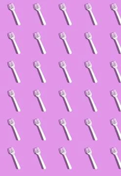 Vertical pattern with white disposable forks with a shadow on a lilac backgro Foto stock