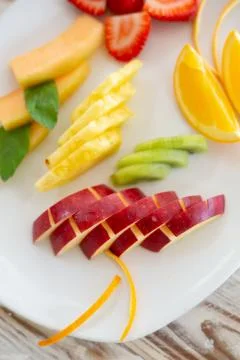 Vertical photo of a fruit salad chopped in a plate with pineapple, strawberri Foto stock