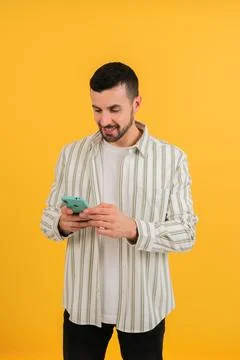 Vertical photo. Isolated guy using his smartphone, cell phone chatting and Stock Photos