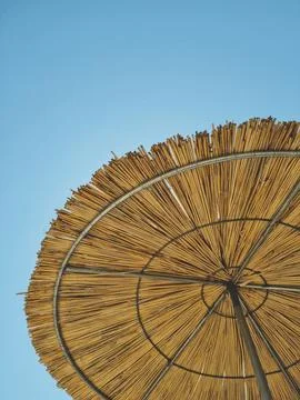 Vertical photo looking down at straw beach umbrella and blue sky. concept o.. Foto stock