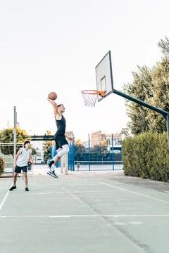 Vertical photo of a man jumping while scoring during a friendly basketball match Stock Photos