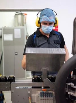 Vertical photo of a man working on a machine in the beer canning production line Stock Photos
