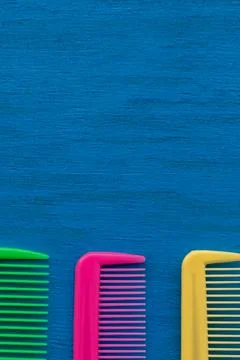 Vertical photo of multi-colored combs on a blue background and copy space. Foto stock