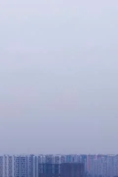A vertical photo of multi-colored high-rise buildings on a gray sky Stock Photos